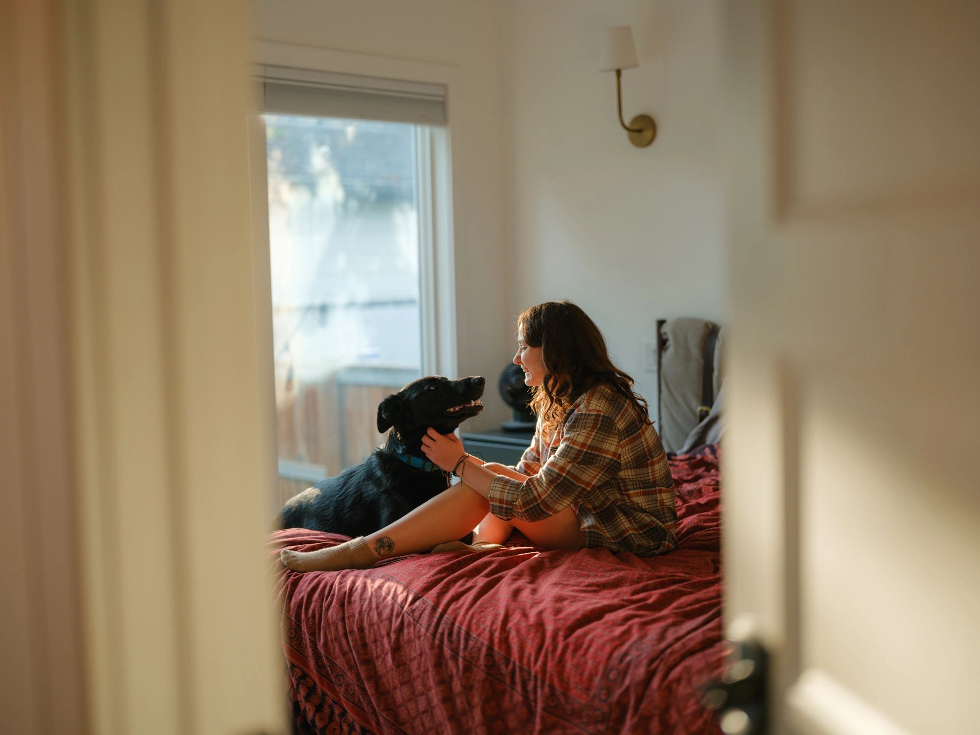 Pet caregiver sitting on a bed with a dog during an in-home visit
